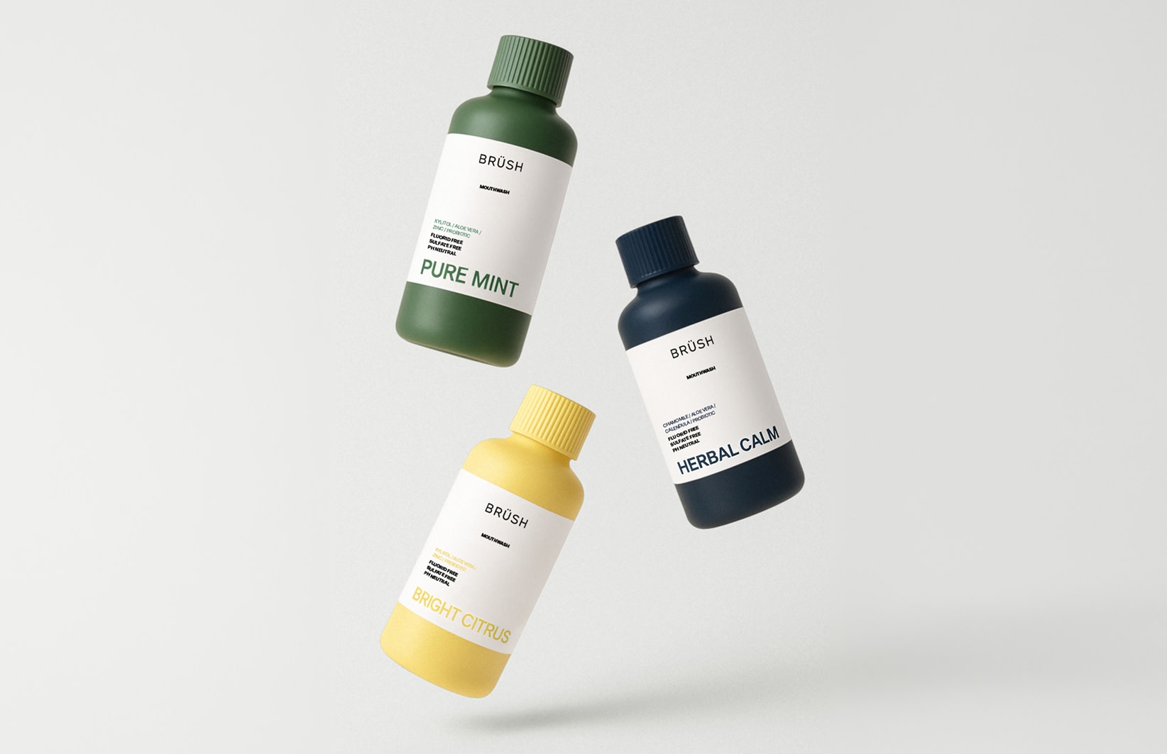 Trois flacons Brüsh flottant sur un fond clair.